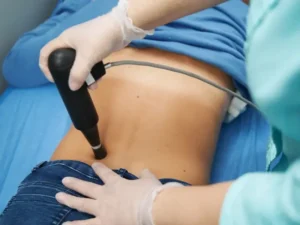 Therapist using non-invasive device for lower back pain relief during physiotherapy session.